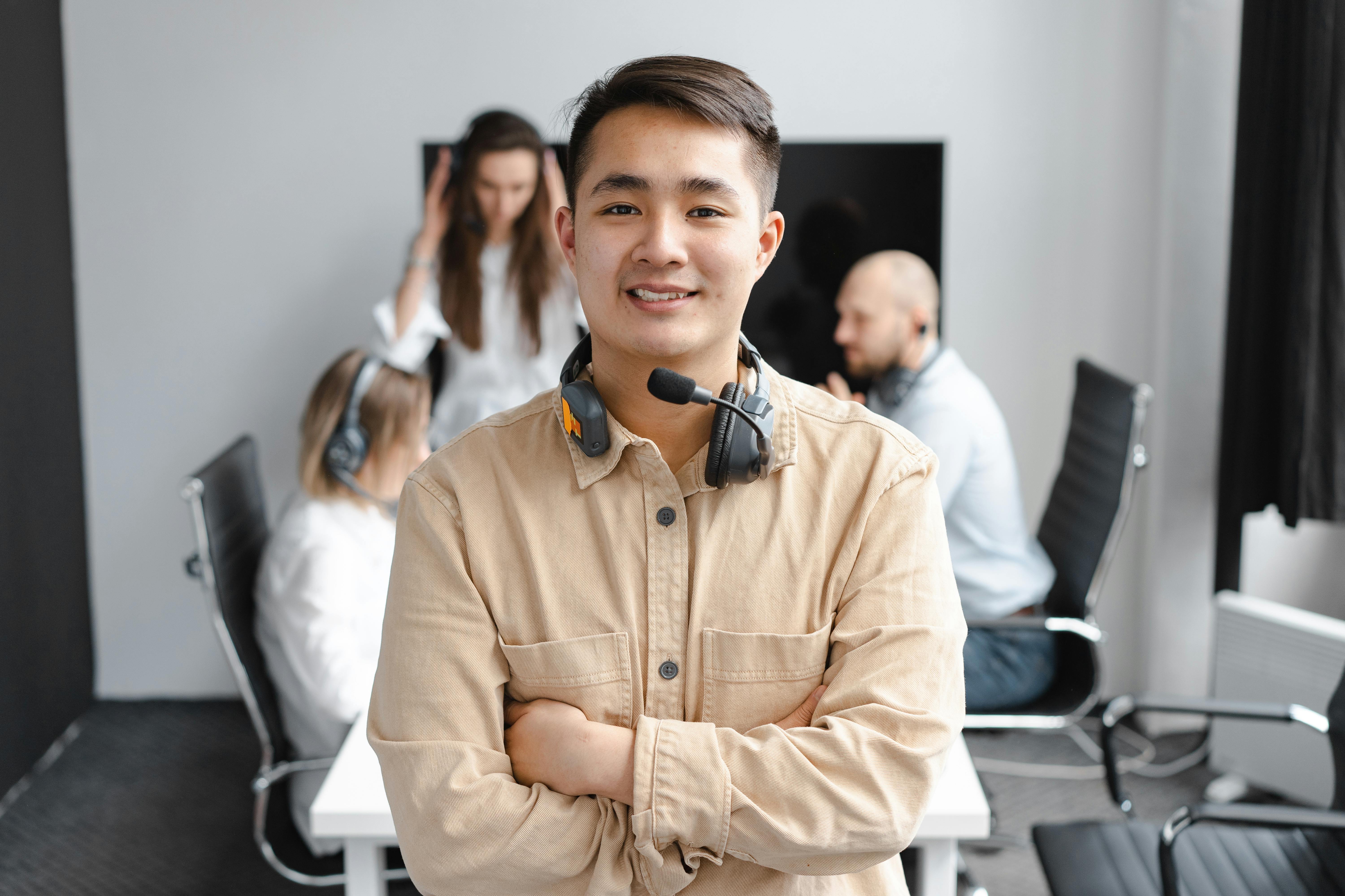 Smiling call center agent with headset in office setting, showcasing teamwork and communication.