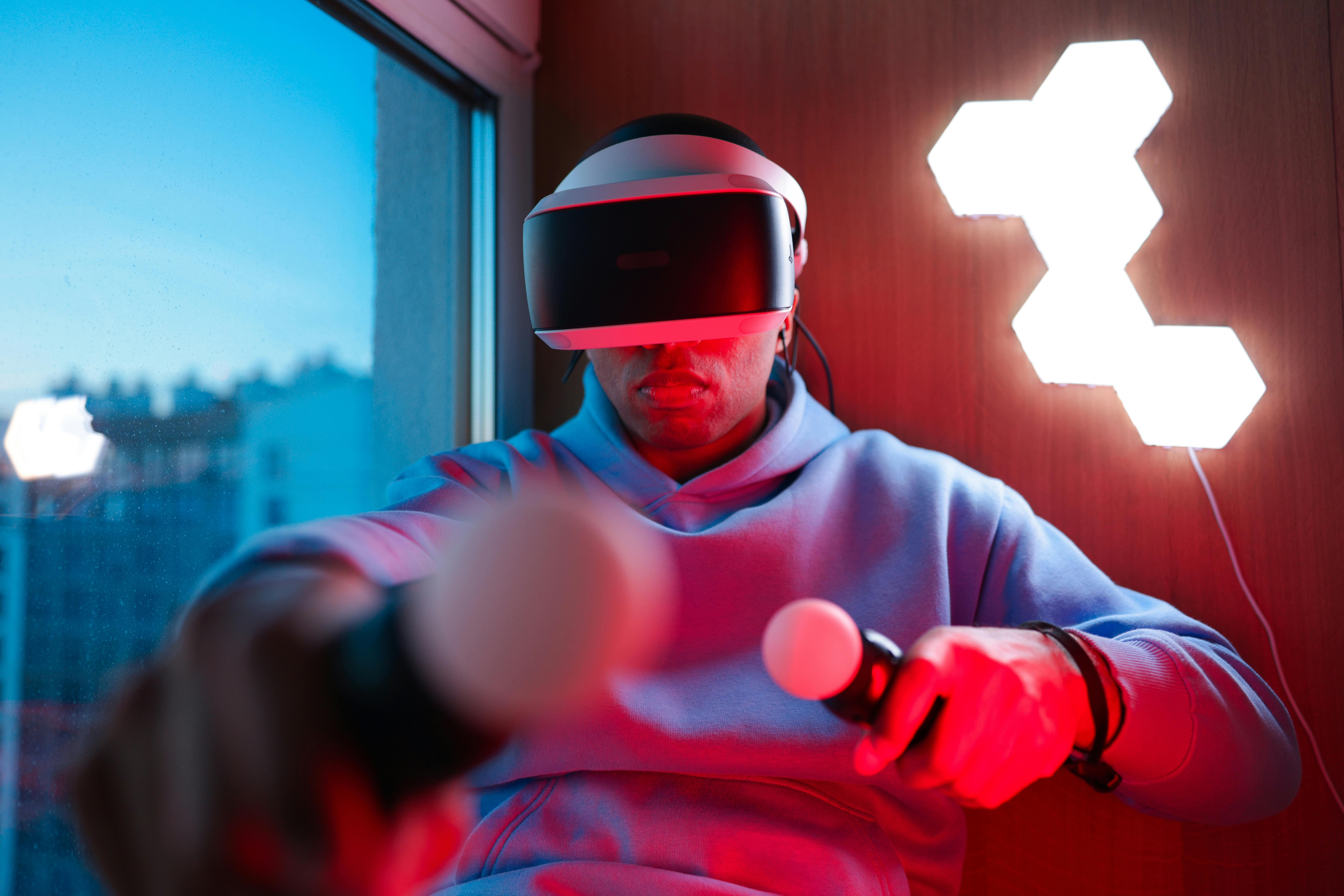 A man plays a virtual reality game using controllers and VR headset indoors.