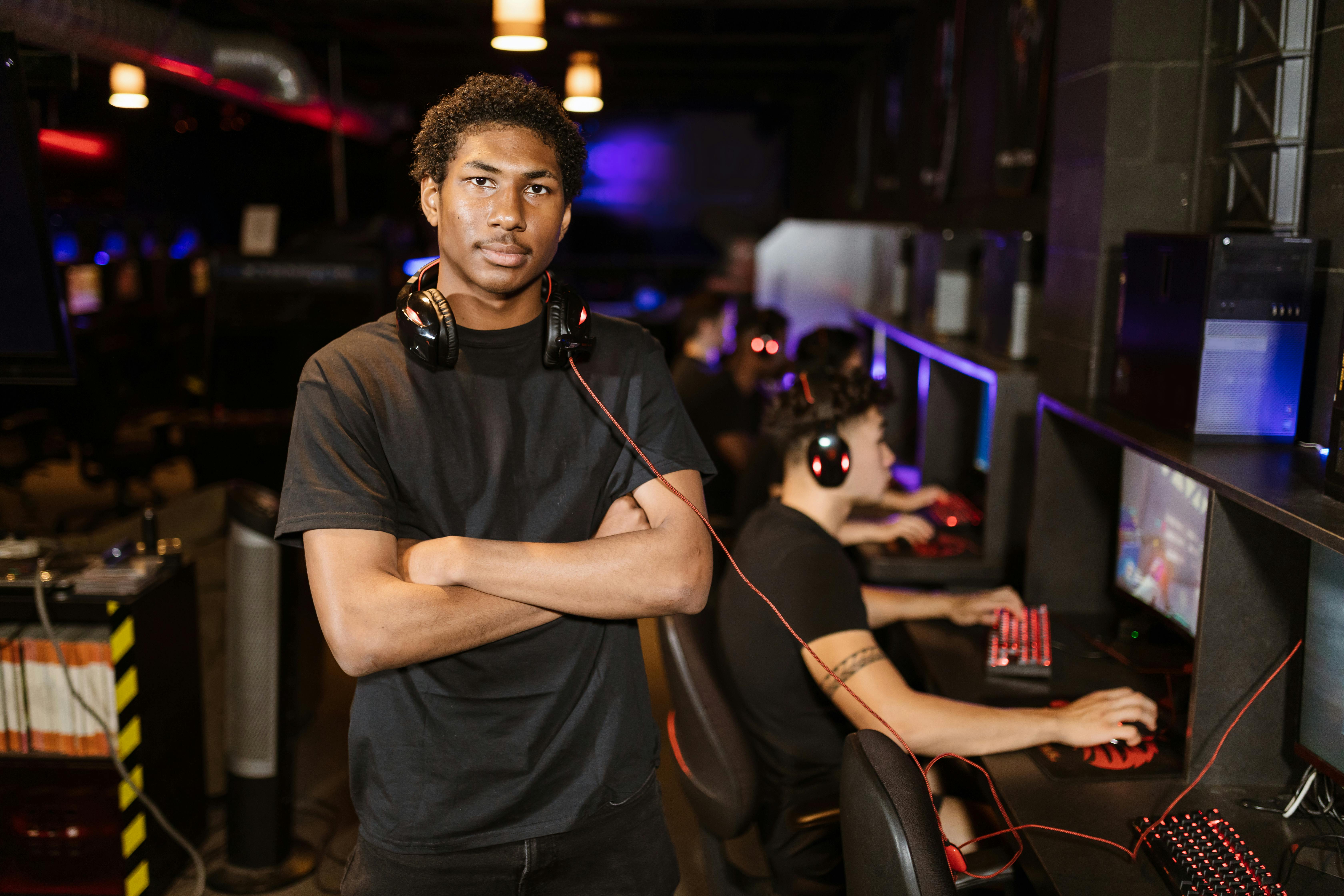 Young gamer standing with arms crossed in an esports arena, exuding confidence.